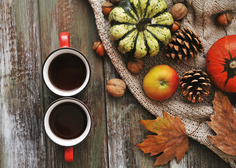 Autumn background. Pumpkins, apples, nuts,leaves, cups and sweater on wooden background.