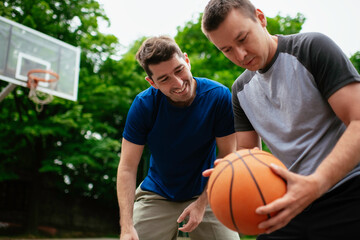 Two young men playing basketball in the park. Friends having a friendly match outdoors	