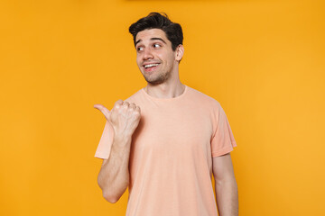 Photo of joyful handsome man smiling and pointing finger aside