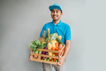 portrait of male delivery courier with grocery shopping on a wooden crate