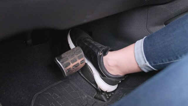 A woman's foot depressing the accelerator pedal of a modern car.
