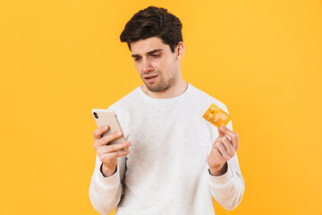 Photo of handsome sick man holding credit card and smartphone