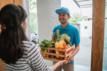 asian male courier delivering grocery to customer. food online delivery