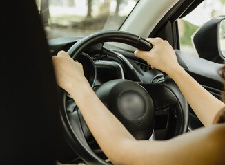 The hands of an Asian tourist woman driving a private car using both hands to hold the steering wheel for travel, learn to drive a car, test drive a car