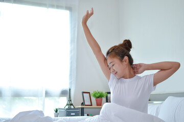 Beautiful Asian woman woke up in the morning on the bed in her bedroom. She feels very fresh.