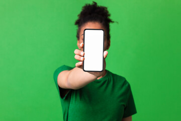 African girl showing white blank cell phone screen at studio
