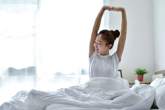 Beautiful Asian woman is happy to wake up in the morning on a bed. She felt very refreshed after a deep sleep all night.