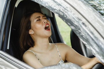 An Asian female tourist is drowsy while driving his private car.