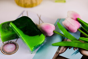 Two pgreen pieces of handmade soap stand on top of each other on a white table. .