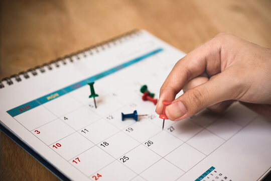 people's hand hold red push pin to mark date on calendar with vignette