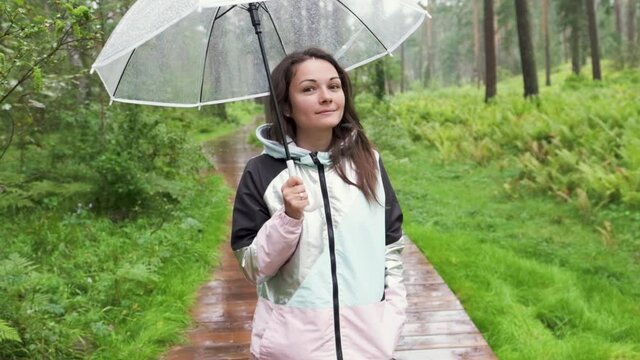 a young woman walks through the woods in the rain with an umbrella. attractive brunette walks in the park in the rain