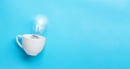 Light bulb in white cup on blue background. Ideas and creative thinking concept.
