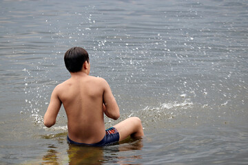 Wet guy in trunks splashing in a water. Beach vacation, enjoying the summer