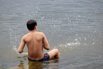 Fototapeta premium Wet guy in trunks splashing in a water. Beach vacation, enjoying the summer