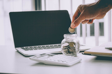 Fototapeta premium saving money with hand putting coins in jug glass concept financial