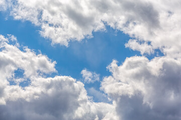 fluffy white clouds against a blue sky backlit by the sun