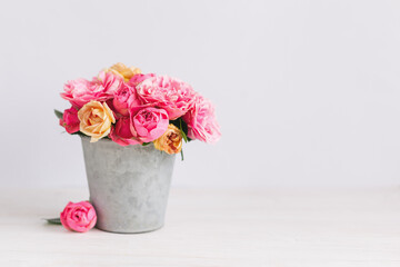 Romantic bouquet of pink and yelloow roses in a vintage pot on a white background.