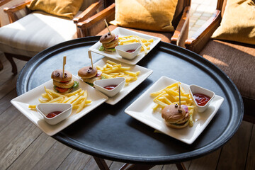 
On a black large tray there are four plates with burgers and a fry pot, taken from the top angle from the side,
burger, fries, french fries, tray, snack, meat, food burger, sandwich