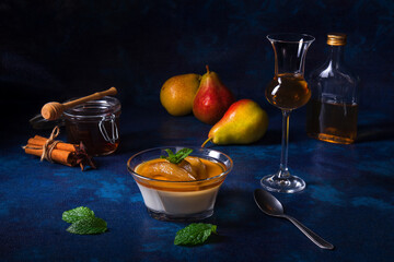 Panna cotta Italian traditional dessert with pears poached in rum and honey syrup. Dark blue...