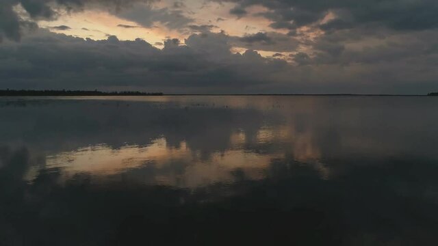 The sky is in zagon with clouds above the pond. Sunset time.