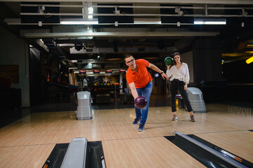 A beautiful loving caucasian couple throwing balls on the bowling alley. Boyfriend and girlfriend at the bowling club