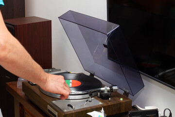 Vinyl record player on a wooden table. Man's hand Turns on the player. Sound technology for DJs to...