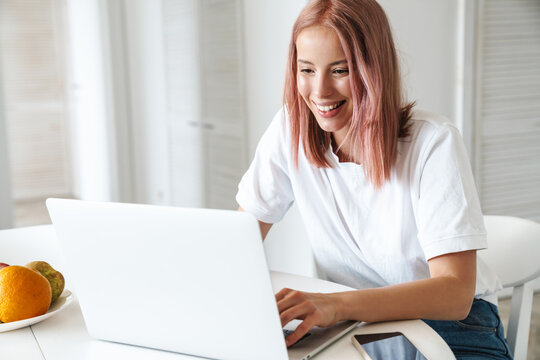 Photo of cheerful woman working with laptop while sitting at table