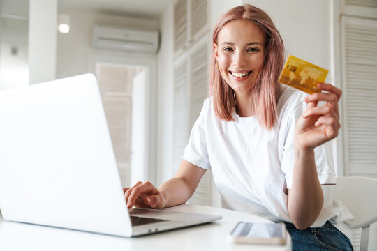 Photo of cheerful woman working with laptop and holding credit card