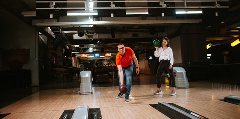 A beautiful loving caucasian couple throwing balls on the bowling alley. Boyfriend and girlfriend at the bowling club