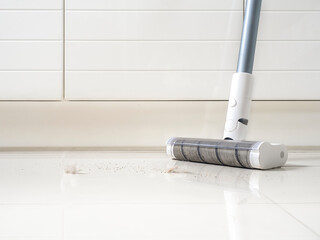 White vacuum cleaner on white floor and wall. Dust and cat fur spot are on the floor. Modern home White tone. Housework concepts.