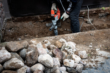 Male worker repairing driveway surface with jackhammer, digging and drilling concrete road.