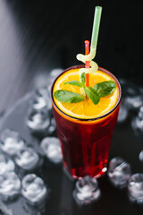 Citrus ice tea with orange and mint on black back ground and ice
