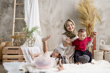 mother and her two children smile when posing looking at the camera in the studio