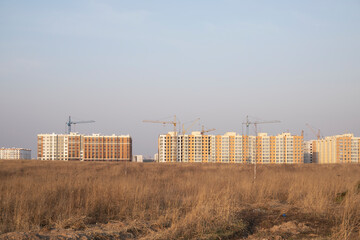 Multi-story complex of houses, construction is underway, cranes are working, construction in progress