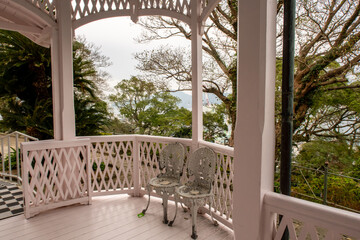Colonial style wooden pink terrace in Glover Gareden with old stylish chairs and trees in the...