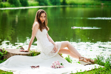 Fototapeta na wymiar Young woman was sitting on a picnic by a lake, summer park outdoor