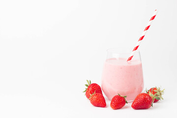 Glass of fresh strawberry milkshake, smoothie and fresh strawberries on pink, white and wooden background. Healthy food and drink concept.