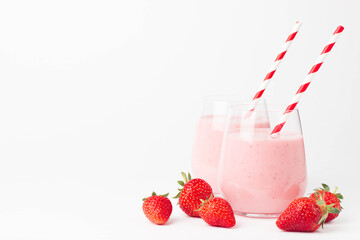 Glass of fresh strawberry milkshake, smoothie and fresh strawberries on pink, white and wooden background. Healthy food and drink concept.