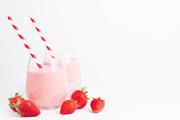 Glass of fresh strawberry milkshake, smoothie and fresh strawberries on pink, white and wooden background. Healthy food and drink concept.