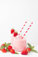 Glass of fresh strawberry milkshake, smoothie and fresh strawberries on pink, white and wooden background. Healthy food and drink concept.