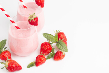 Glass of fresh strawberry milkshake, smoothie and fresh strawberries on pink, white and wooden background. Healthy food and drink concept.