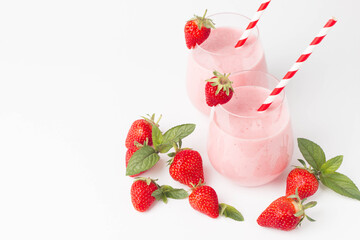 Glass of fresh strawberry milkshake, smoothie and fresh strawberries on pink, white and wooden background. Healthy food and drink concept.