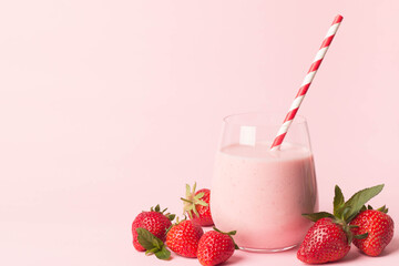 Glass of fresh strawberry milkshake, smoothie and fresh strawberries on pink, white and wooden background. Healthy food and drink concept.