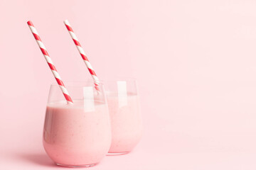 Glass of fresh strawberry milkshake, smoothie and fresh strawberries on pink, white and wooden background. Healthy food and drink concept.