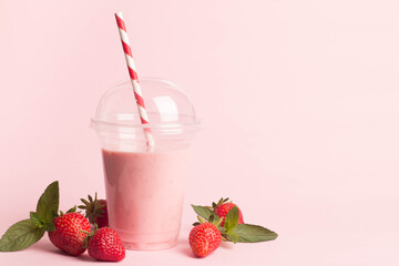 Glass of fresh strawberry milkshake, smoothie and fresh strawberries on pink, white and wooden background. Healthy food and drink concept.