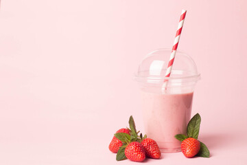 Glass of fresh strawberry milkshake, smoothie and fresh strawberries on pink, white and wooden background. Healthy food and drink concept.