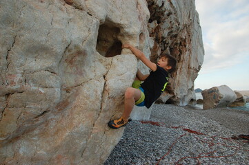  little boy climbs on the rock
