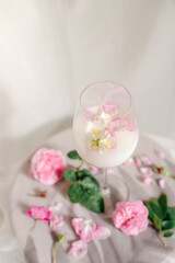 Glass with milk and roses on the table