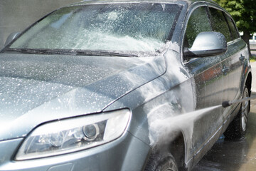 Full car wash at the self service. Splashed drops of water from a sprayer washing the car. Windshield. White foam