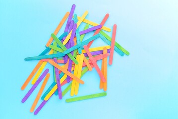 Colorful wood sticks used for creating art shapes/objects. Rainbow color sticks on a blue background.